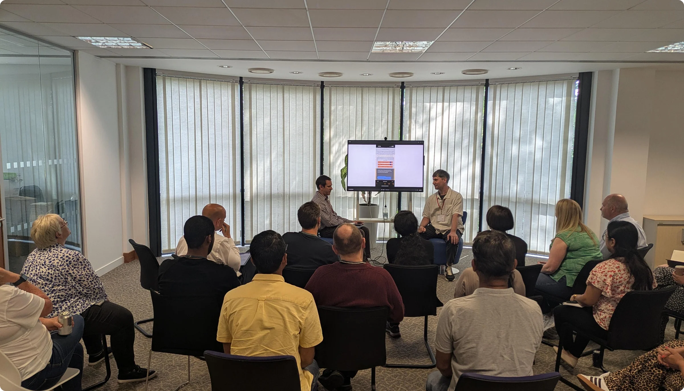 Two men presenting with a large screen, one demonstrating mobile accessibility as a blind user