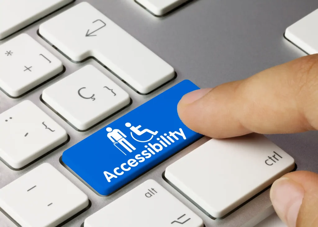 Close-up of a keyboard with a finger pressing a blue 'Accessibility' key featuring disability icons