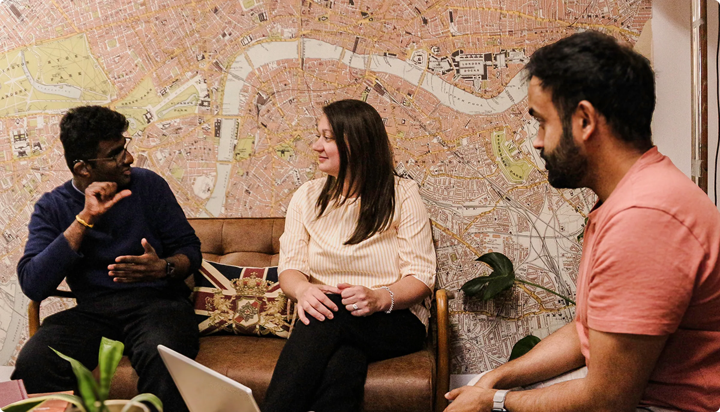 Two men and one woman seated together, with one man signing to the woman