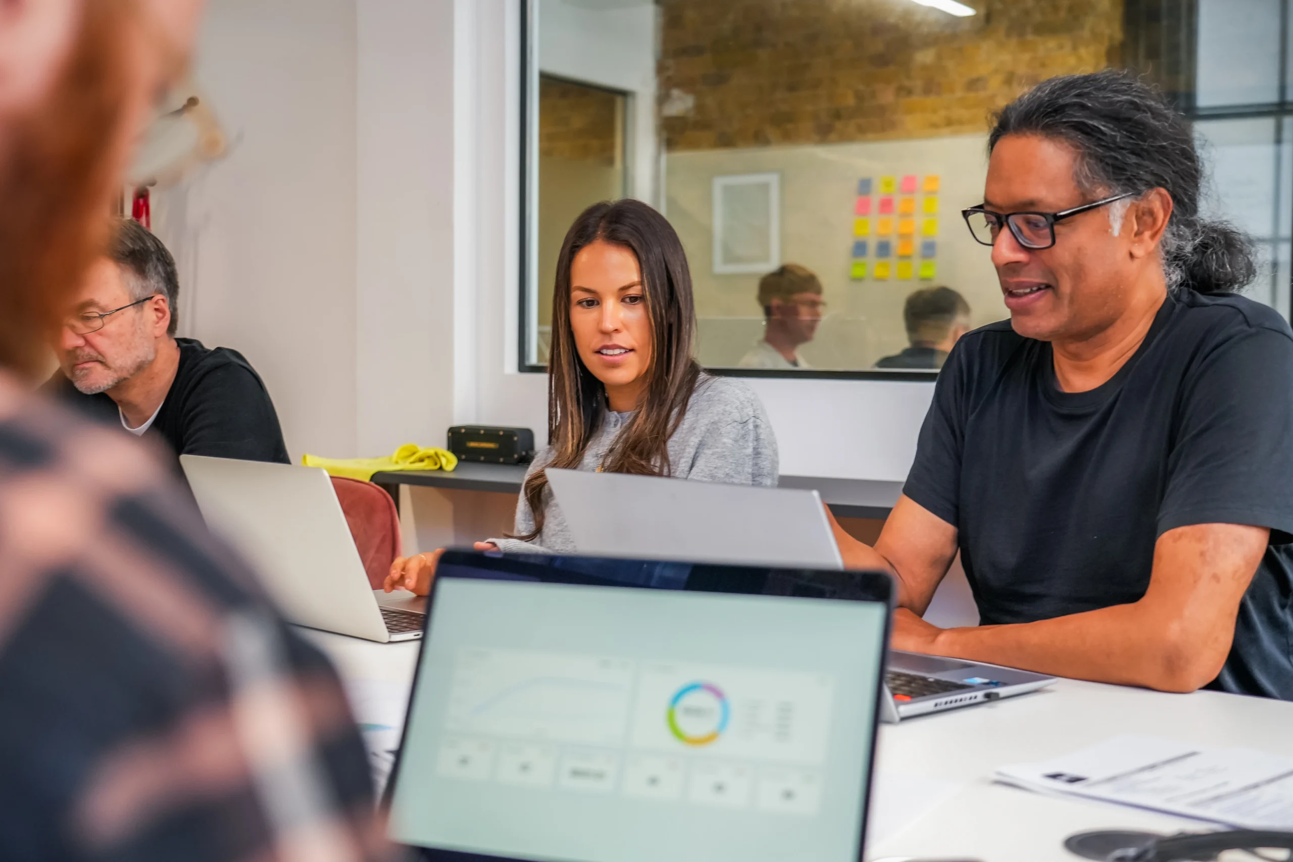 Two developers collaborating with laptops open during a team working session on accessibility.